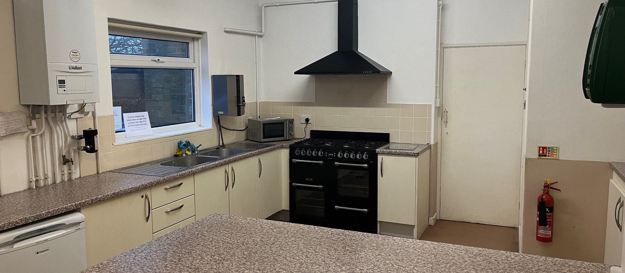 There is a large fitted kitchen at the hall with plenty of workspace. A double sized cooker, a fridge and microwave oven. There is also a dining area at the other end of the room.